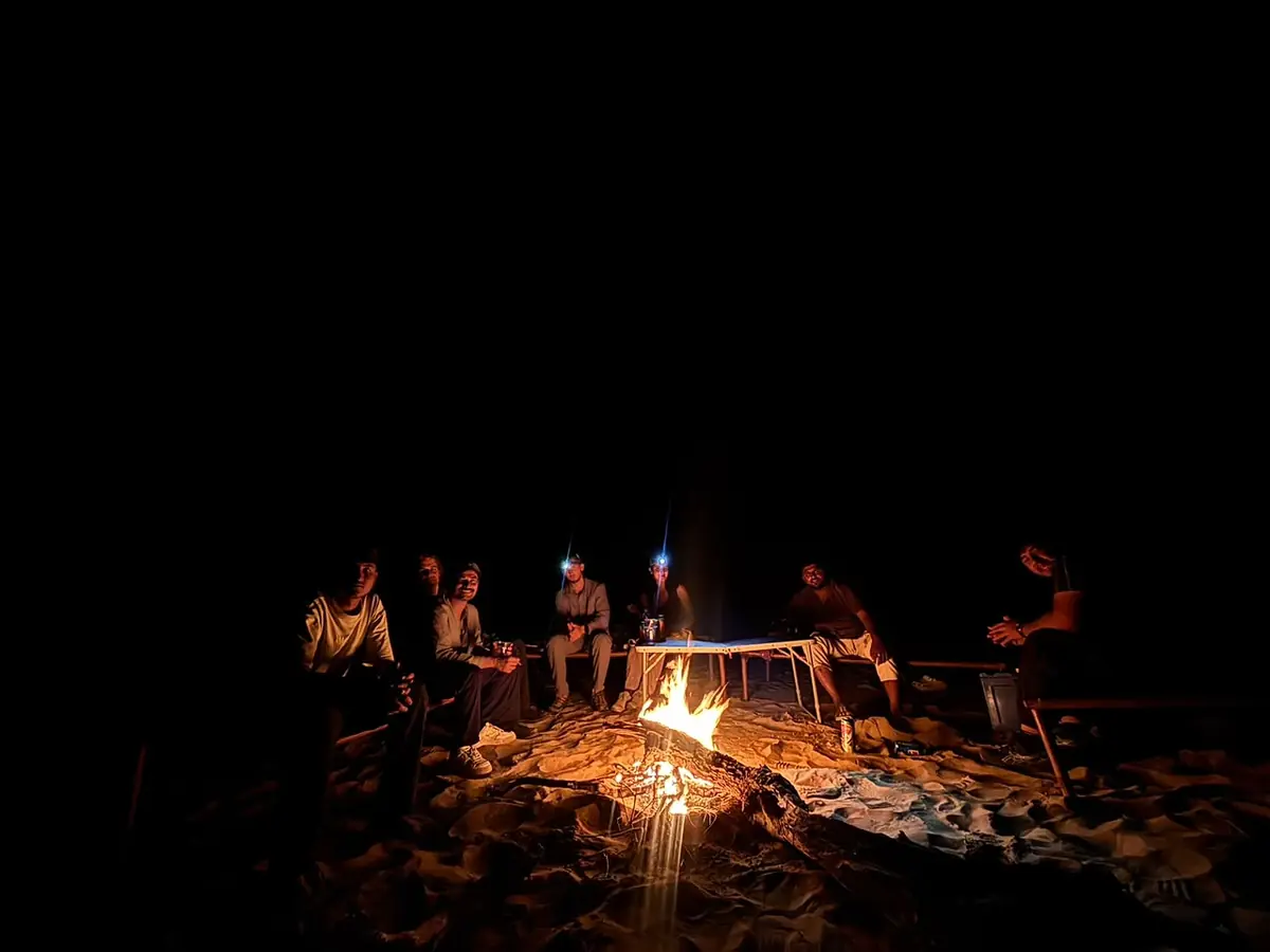 Travellers around a bonfire at night on a Thar desert safari