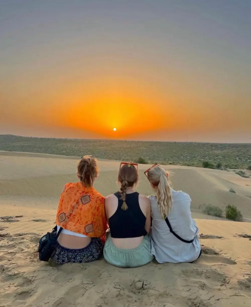 Three travellers watching the sunset from the sand dunes near Jaisalmer